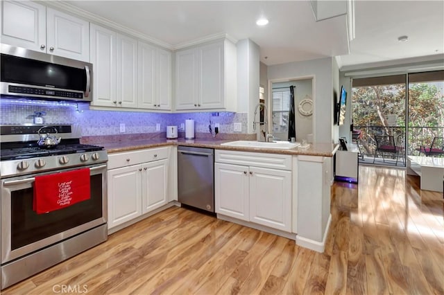 2230 Watermarke Pl, Irvine, CA 92612 - kitchen featuring stainless steel appliances, a sink, light wood finished floors, white cabinets, and recessed lighting