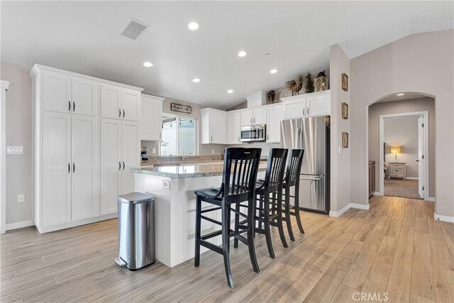 5824 White Fox Trl, Phelan, CA 92371 - kitchen with appliances with stainless steel finishes, arched walkways, lofted ceiling, light wood finished floors, and white cabinets