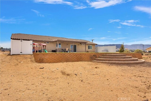 5824 White Fox Trl, Phelan, CA 92371 - back of house with a playground, stucco siding, a tiled roof, and a mountain view