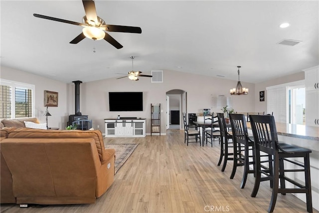 5824 White Fox Trl, Phelan, CA 92371 - living room with a wood stove, a ceiling fan, light wood-style flooring, vaulted ceiling, and arched walkways