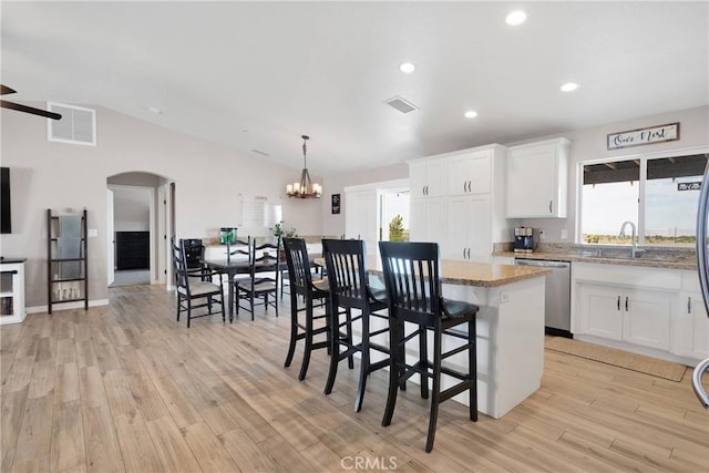 5824 White Fox Trl, Phelan, CA 92371 - kitchen with stainless steel dishwasher, arched walkways, light wood-type flooring, a sink, and white cabinetry