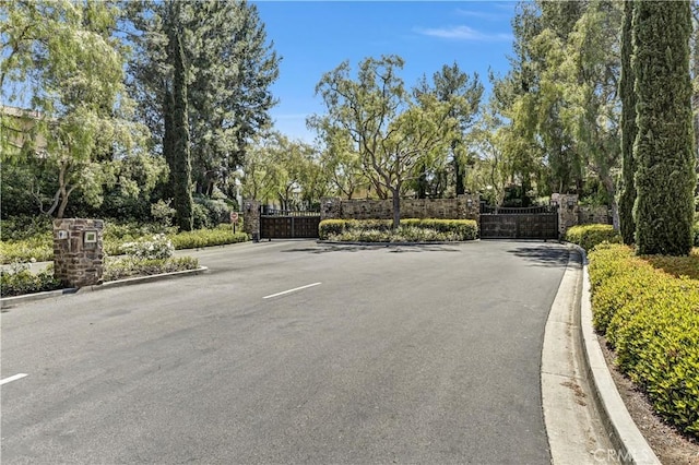 86 Canyoncrest, Irvine, CA 92603 - view of asphalt road with a gate, curbs, and a gated entry