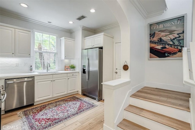 86 Canyoncrest, Irvine, CA 92603 - kitchen featuring stainless steel appliances, a sink, arched walkways, crown molding, and white cabinets