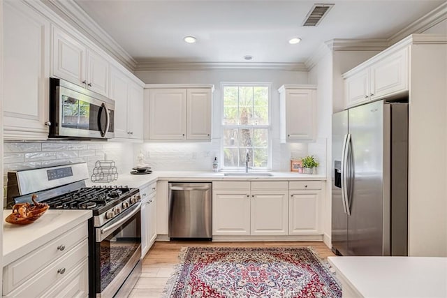 86 Canyoncrest, Irvine, CA 92603 - kitchen with stainless steel appliances, a sink, light wood-style flooring, white cabinetry, and light countertops