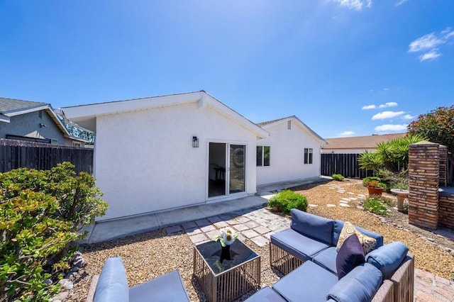 back of property with a patio, an outdoor living space, stucco siding, and a fenced backyard