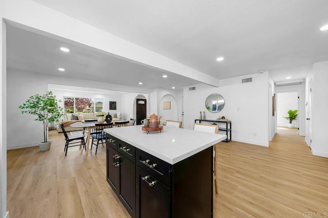 8184 Flanders Dr, San Diego, CA 92126 - kitchen with a kitchen island, light countertops, light wood-type flooring, recessed lighting, and arched walkways