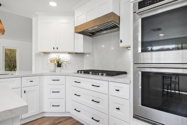 1707 Willowhaven Rd, Encinitas, CA 92024 - kitchen featuring stainless steel appliances, wall chimney exhaust hood, light stone countertops, decorative backsplash, and white cabinetry