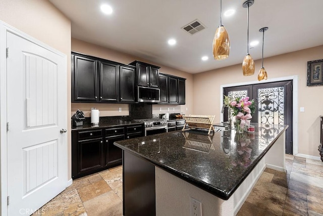 5801 S Moonstone Peak Dr, Bakersfield, CA 93313 - kitchen with stone tile flooring, dark cabinetry, stainless steel appliances, dark stone counters, and baseboards
