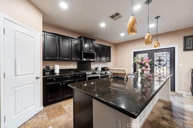 5801 S Moonstone Peak Dr, Bakersfield, CA 93313 - kitchen featuring dark cabinets, stone tile floors, stainless steel appliances, dark stone counters, and a spacious island