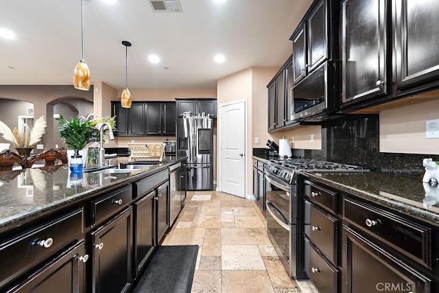 5801 S Moonstone Peak Dr, Bakersfield, CA 93313 - kitchen featuring stainless steel appliances, stone tile flooring, dark stone countertops, hanging light fixtures, and recessed lighting