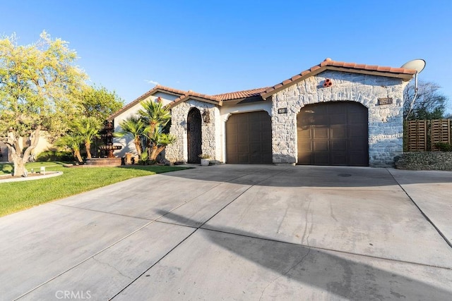 5801 S Moonstone Peak Dr, Bakersfield, CA 93313 - mediterranean / spanish-style home featuring an attached garage, stone siding, driveway, and a tiled roof