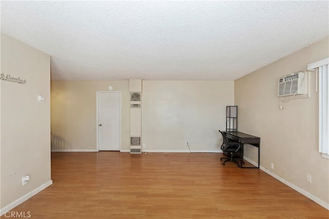 16193 Colina St, Victorville, CA 92395 - unfurnished room with a wall mounted AC, light wood-type flooring, a textured ceiling, and baseboards