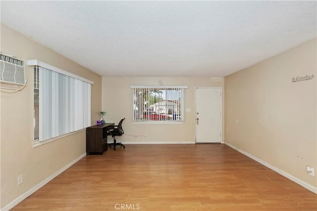 16193 Colina St, Victorville, CA 92395 - unfurnished office featuring light wood finished floors, baseboards, a wall mounted AC, and a textured ceiling
