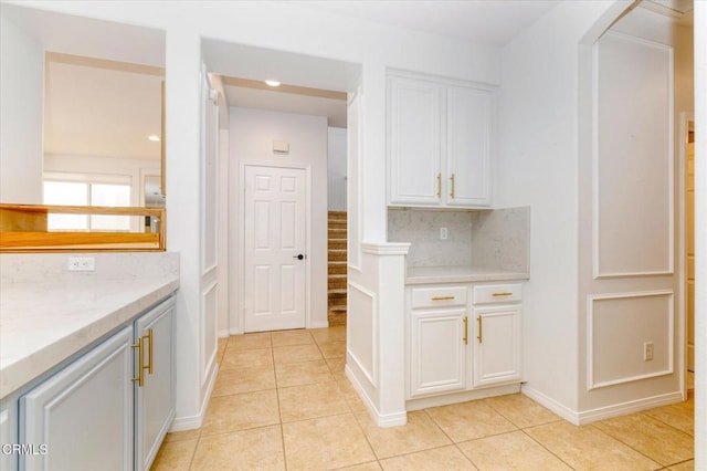 23839 Rio Ranch Way, Valencia, CA 91354 - kitchen featuring light tile patterned flooring, backsplash, white cabinets, and baseboards