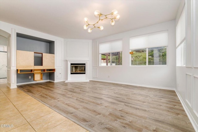 23839 Rio Ranch Way, Valencia, CA 91354 - unfurnished living room featuring a chandelier, wood finished floors, a glass covered fireplace, and baseboards