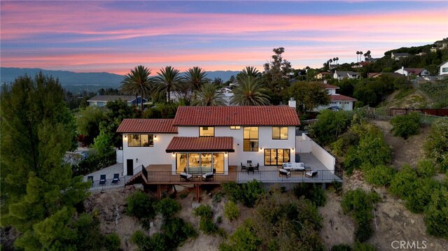 4335 Chaumont Rd, Woodland Hills, CA 91364 - back of house at dusk featuring a tile roof, stucco siding, a chimney, and fence