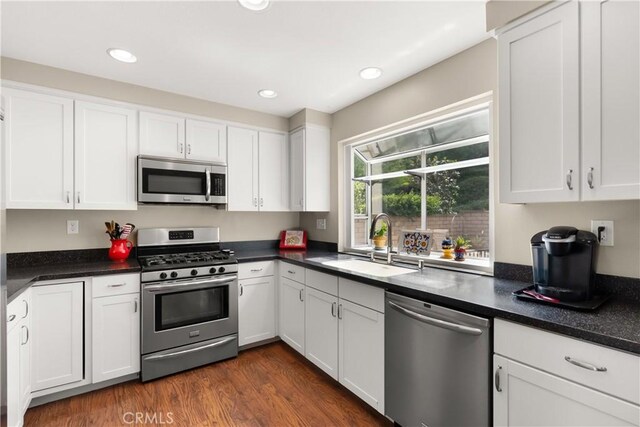 21242 Bristlecone, Mission Viejo, CA 92692 - kitchen with stainless steel appliances, a sink, white cabinets, dark countertops, and dark wood finished floors