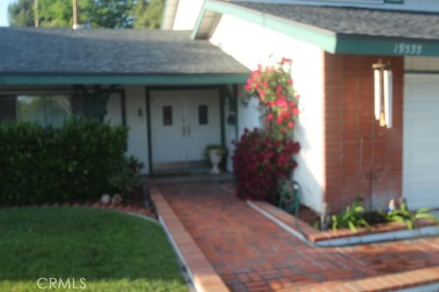 19555 Chadway St, Canyon Country, CA 91351 - view of exterior entry with covered porch, a shingled roof, and a garage