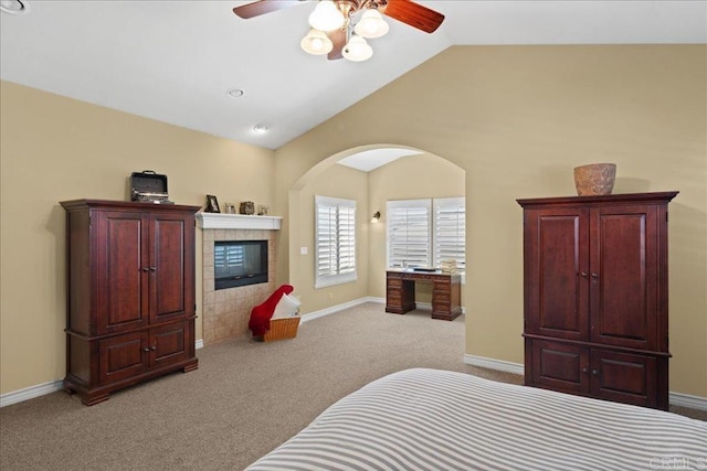 38161 Butterfly Ct, Yucaipa, CA 92399 - carpeted bedroom featuring vaulted ceiling, baseboards, a tile fireplace, ceiling fan, and arched walkways