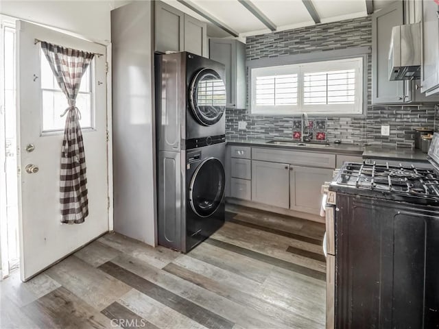 1401 W 165th St, Compton, CA 90220 - washroom with stacked washing machine and dryer, a sink, and light wood-style floors
