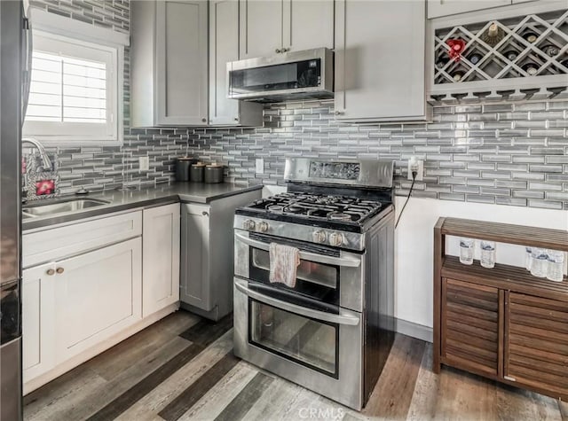 1401 W 165th St, Compton, CA 90220 - kitchen featuring appliances with stainless steel finishes, a sink, decorative backsplash, and dark wood-type flooring