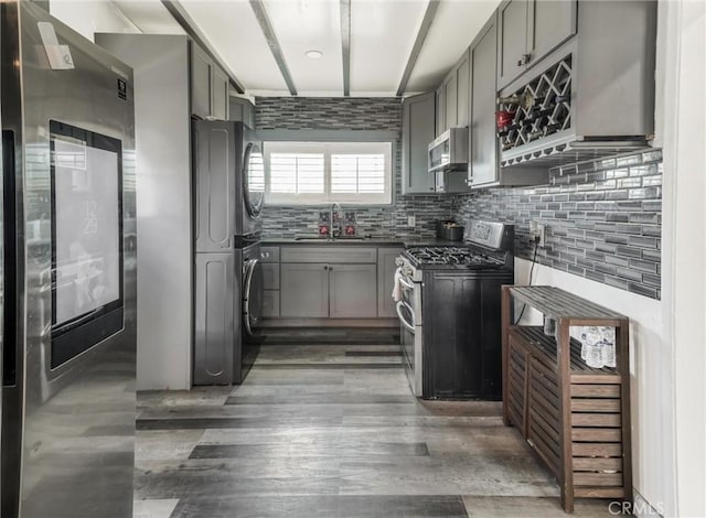 1401 W 165th St, Compton, CA 90220 - kitchen with stainless steel appliances, gray cabinetry, a sink, stacked washer / drying machine, and tasteful backsplash
