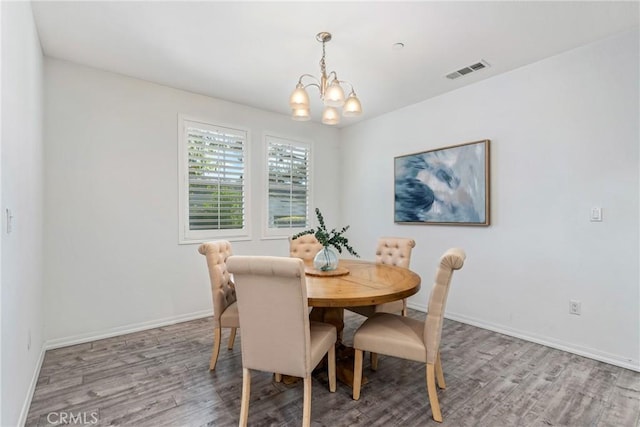 dining area with a chandelier, wood finished floors, and baseboards
