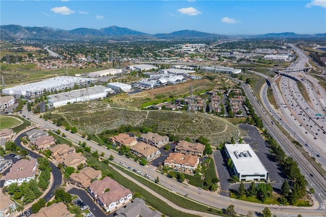 aerial view of property and surrounding area with a major roadway, a mountain backdrop, and nearby suburban area