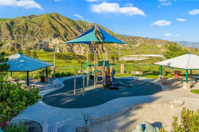 community play area featuring a mountain view and fence