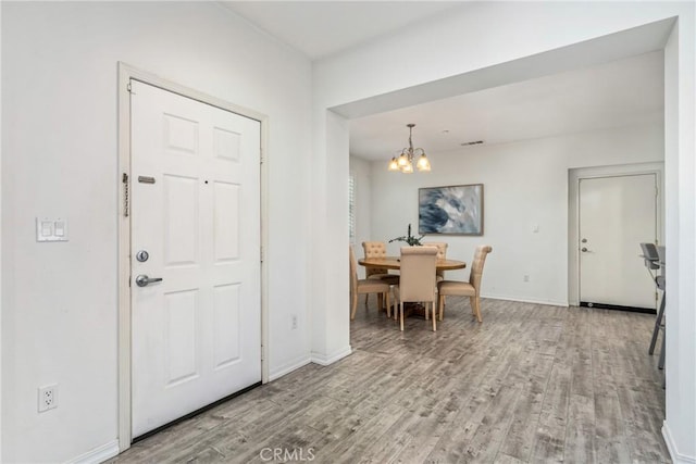 foyer with a chandelier, wood finished floors, and baseboards