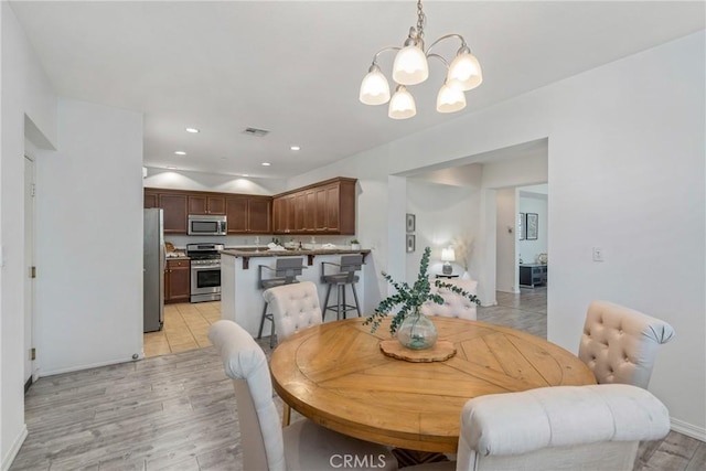 dining space featuring a chandelier, light wood-style floors, recessed lighting, and baseboards