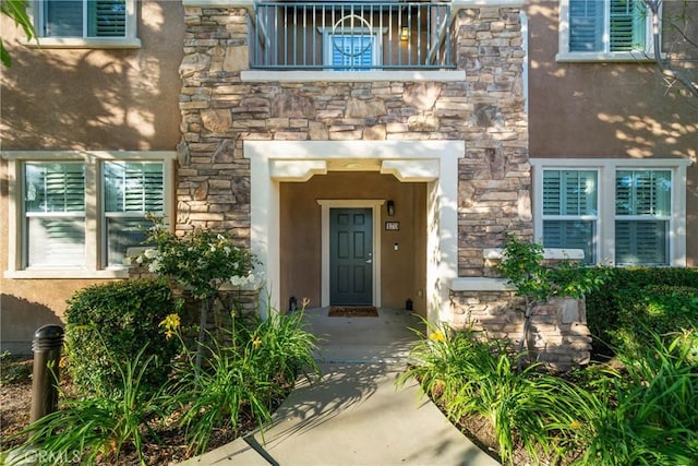 view of exterior entry featuring stone siding and stucco siding