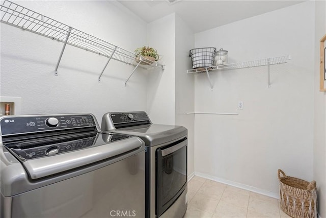 washroom featuring washer and dryer, baseboards, and light tile patterned flooring
