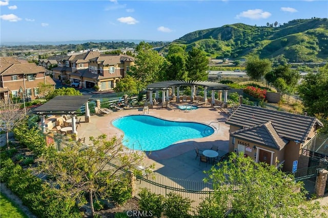 community pool featuring a pergola, fence, a patio area, and a mountain view
