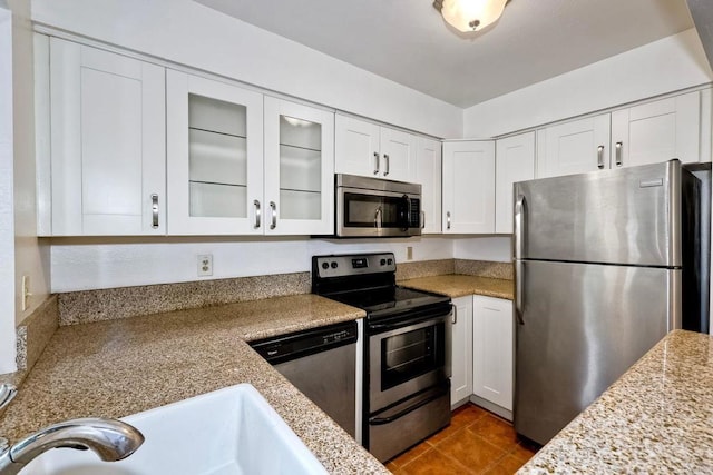 1307 Caminito Gabaldon Unit B, San Diego, CA 92108 - kitchen with appliances with stainless steel finishes, white cabinets, dark tile patterned flooring, glass insert cabinets, and light stone countertops