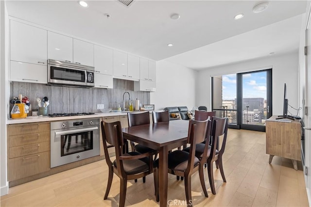 400 S Broadway Unit 2004, Los Angeles, CA 90013 - kitchen with appliances with stainless steel finishes, white cabinetry, light wood-style floors, tasteful backsplash, and recessed lighting