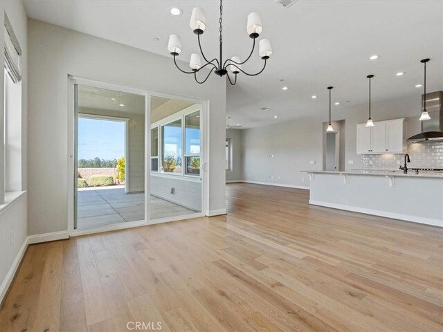 920 Trail View Pl, Nipomo, CA 93444 - unfurnished living room featuring light wood-style flooring, recessed lighting, a chandelier, baseboards, and a sink
