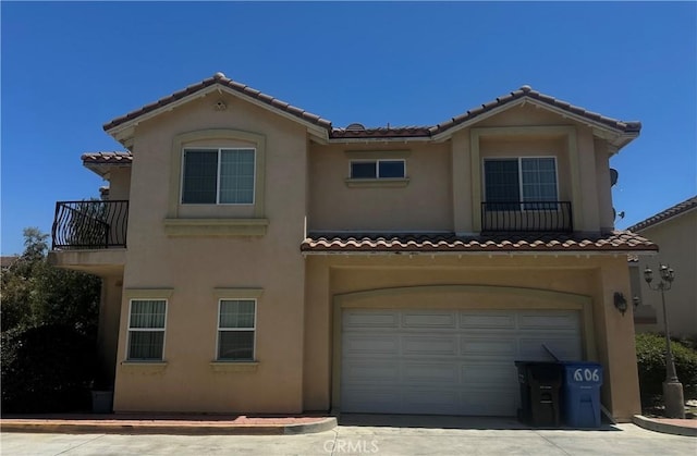 view of front of house with a tile roof, concrete driveway, an attached garage, and stucco siding