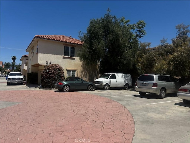 view of front of house featuring stucco siding, uncovered parking, and a tile roof