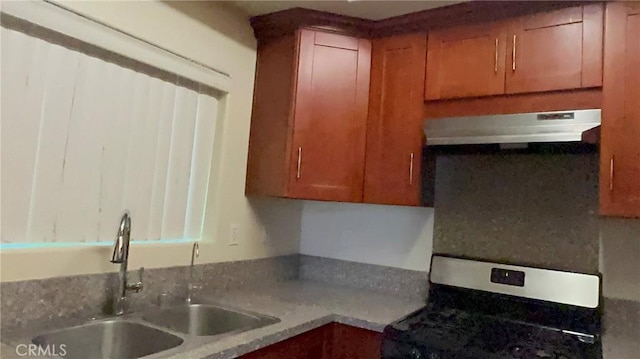 kitchen with stainless steel range with gas cooktop, a sink, under cabinet range hood, and brown cabinets