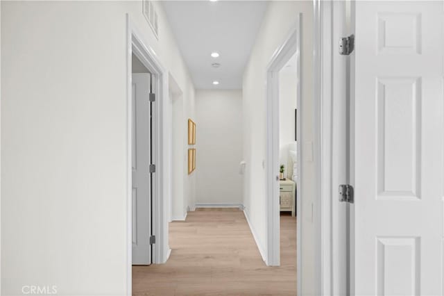 hall featuring light wood finished floors, baseboards, and recessed lighting