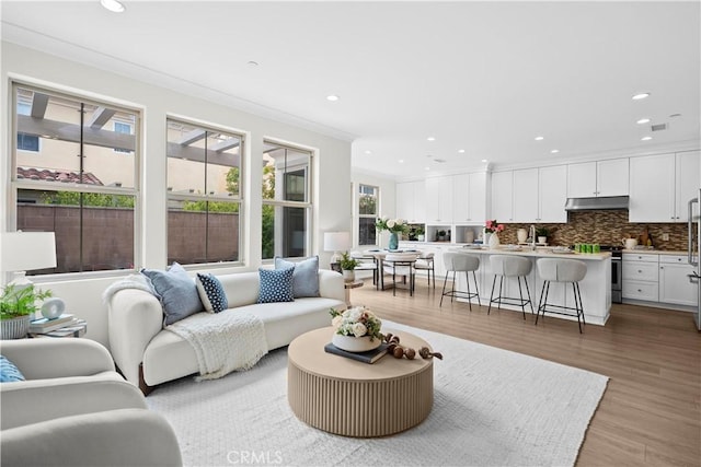living area featuring light wood finished floors, recessed lighting, and crown molding