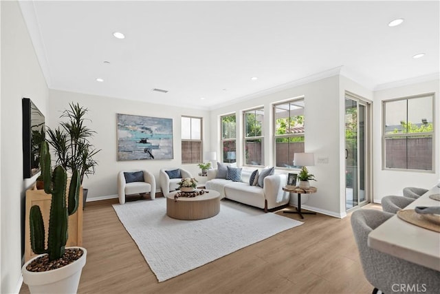 living area featuring baseboards, crown molding, light wood finished floors, and recessed lighting