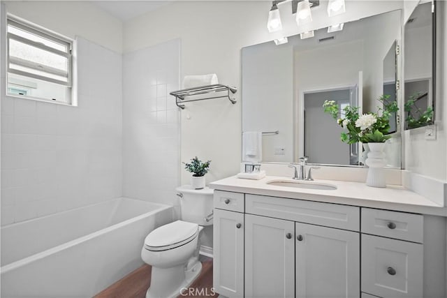 bathroom featuring toilet, vanity, wood finished floors, and shower / washtub combination