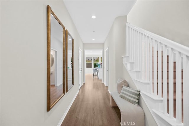 hall featuring wood finished floors, recessed lighting, and baseboards