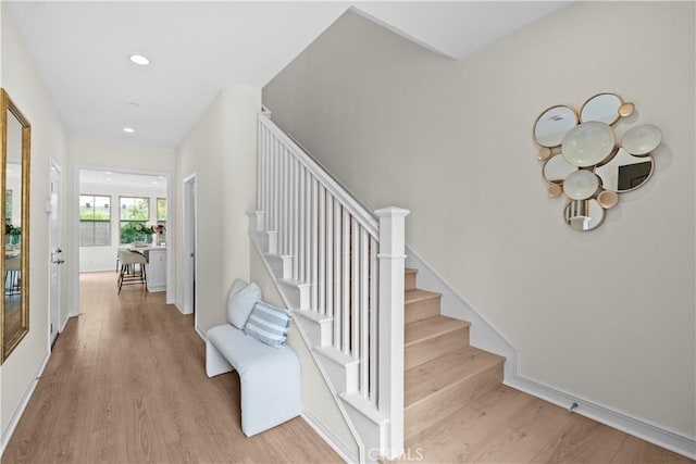 stairs featuring wood finished floors and recessed lighting