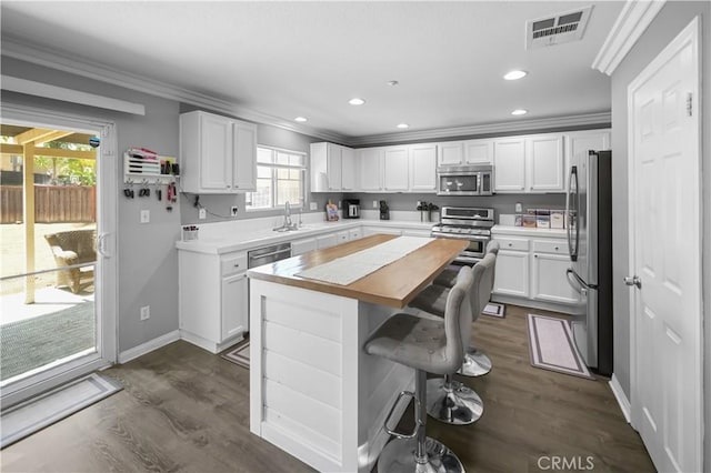 19883 San Juan Capistrano Ct, Riverside, CA 92508 - kitchen featuring stainless steel appliances, crown molding, a center island, white cabinetry, and dark wood-style flooring