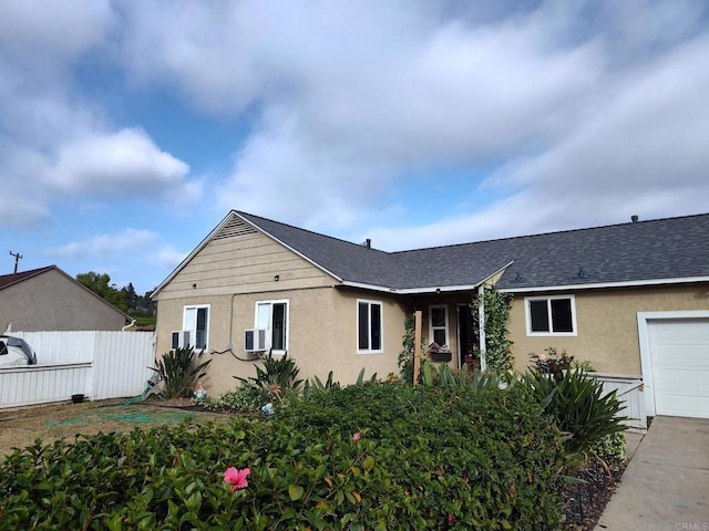 ranch-style home with stucco siding, roof with shingles, and a garage