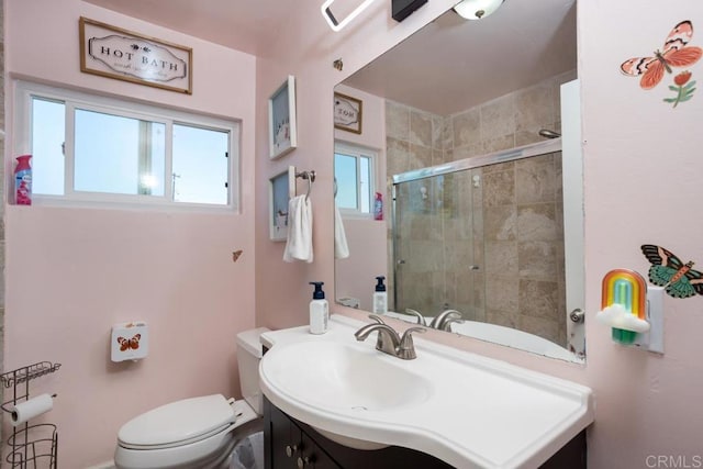 full bathroom featuring tiled shower, toilet, and vanity