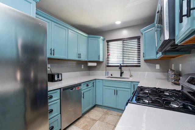 kitchen featuring appliances with stainless steel finishes, a sink, blue cabinetry, and light countertops